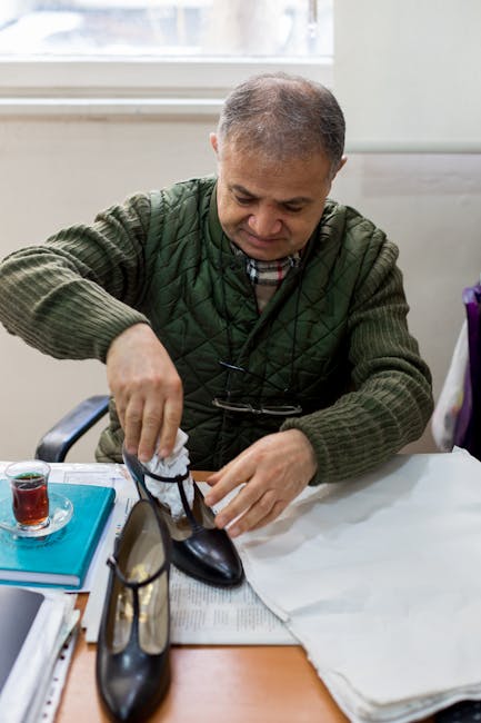 Pensive ethnic man in casual clothes sitting at table with documents and packing new shoes in light room