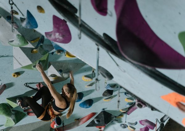 A woman demonstrates strength and agility on an indoor climbing wall.