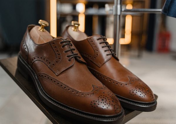 Classic brown leather brogue shoes with detailed perforations on a stylish display.